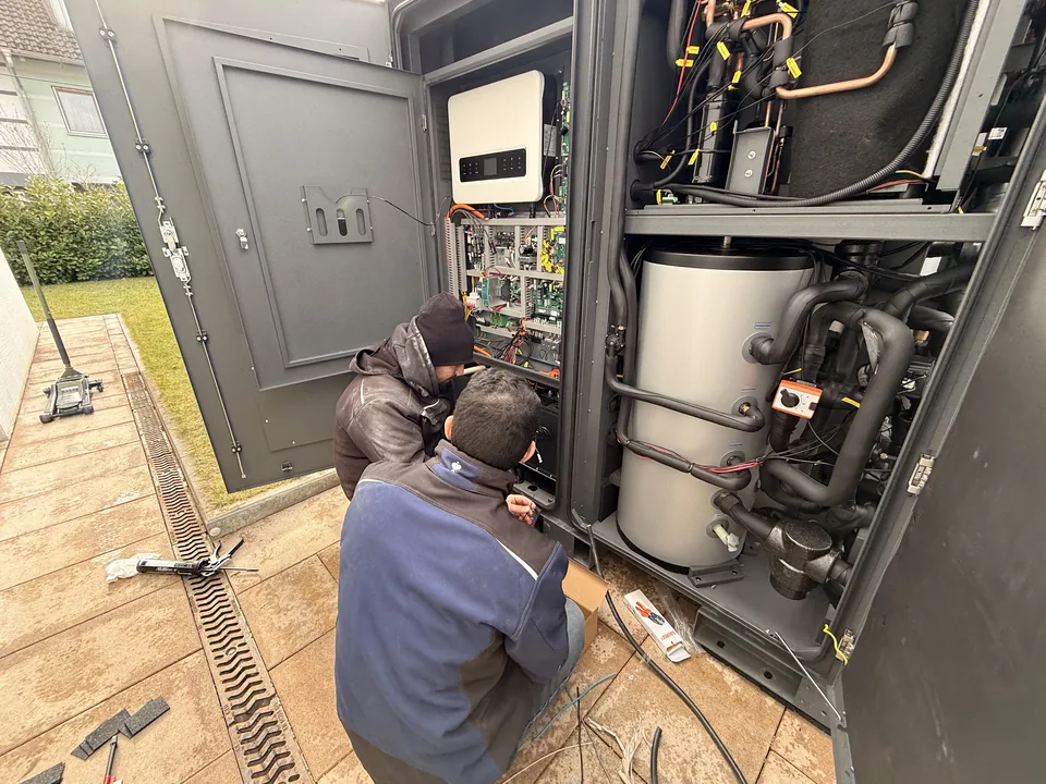 Nahaufnahme der geöffneten Technik mit sichtbarer Verkabelung und Wärmepumpe