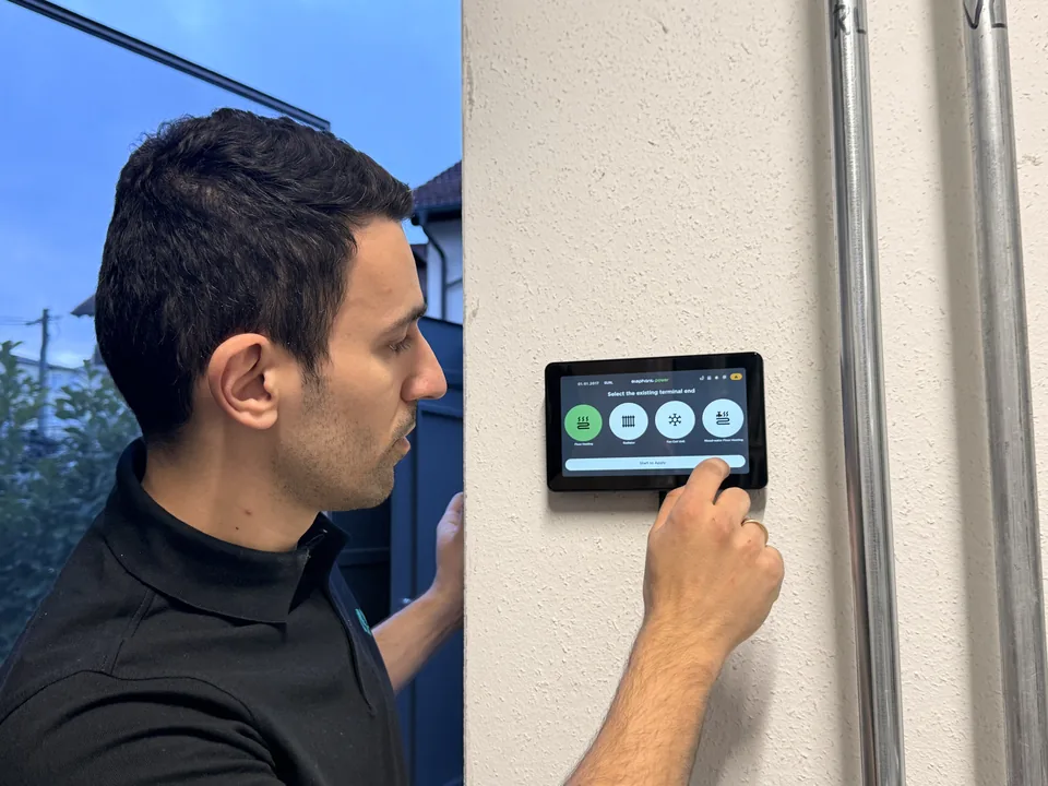 Eine Person bedient das Tablet-Bedienfeld an der Wand